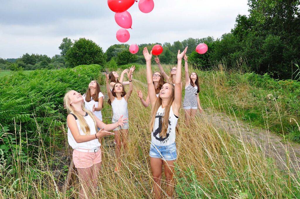 Group of young women celebrating joyfully in a field with balloons