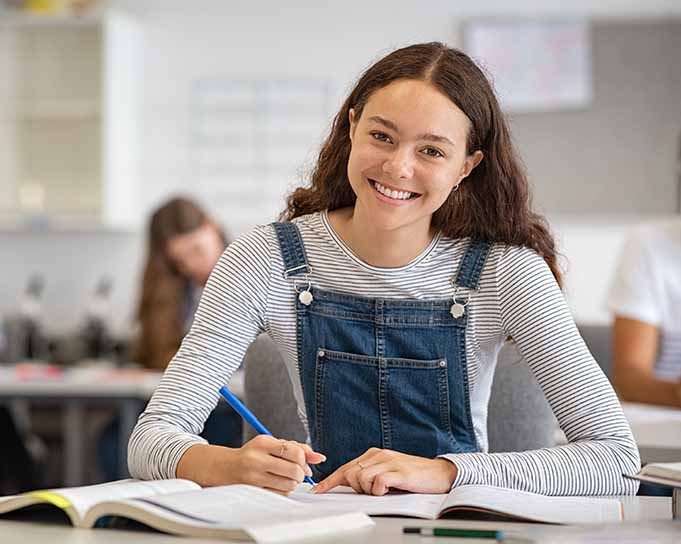 Teenage girl smiling and writing in a notebook